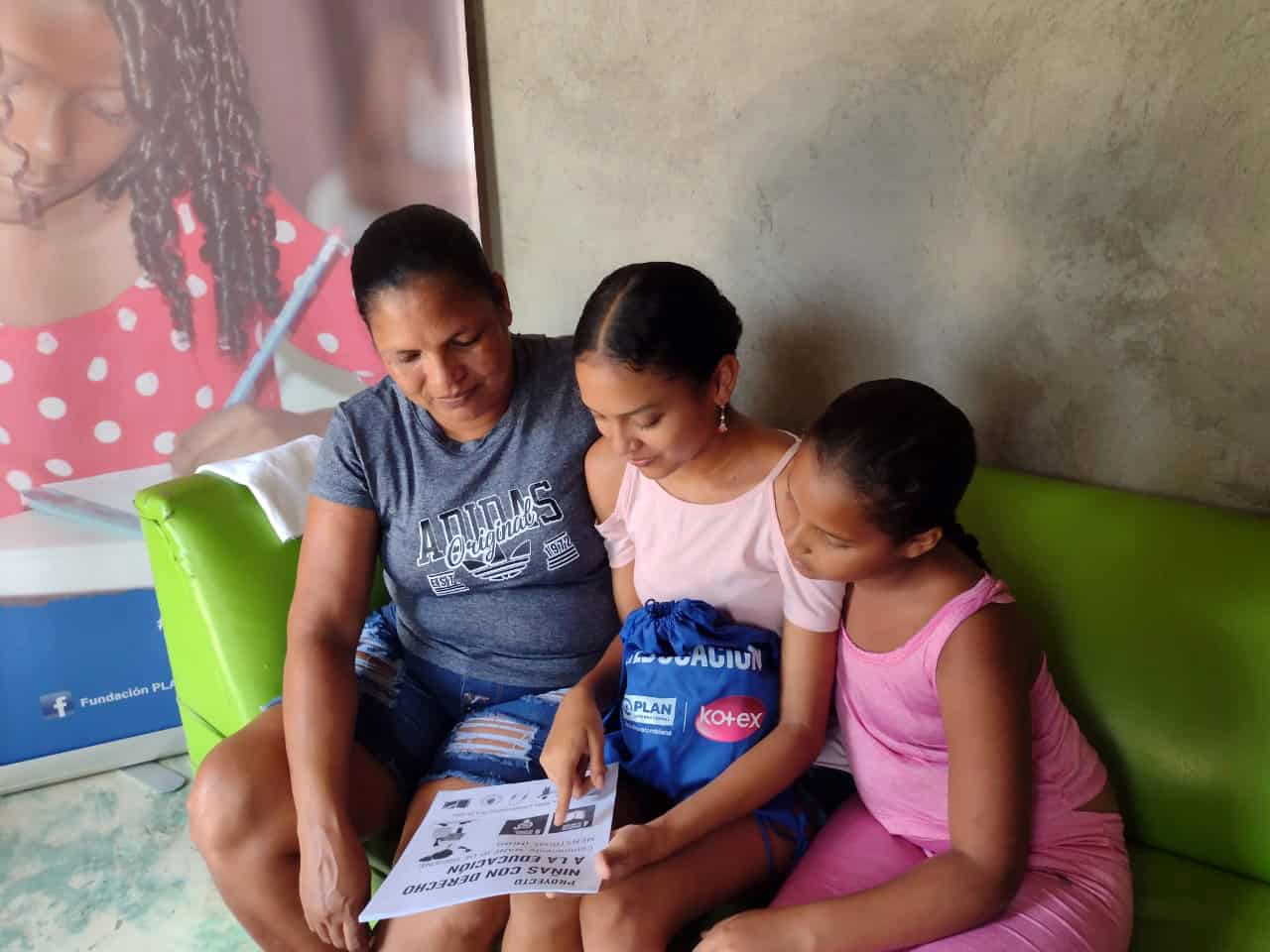 Yacira, a 16-year-old from Colombia, reads information on menstrual health with her mother and younger sister.
